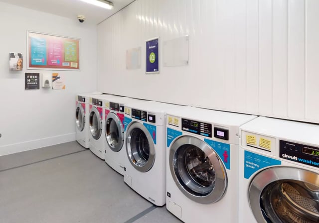 Row of circuit washing machines laundry area at iQ Magenta House in London Student Accommodation