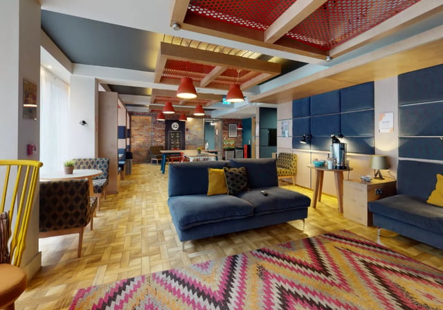 Blue sofa colourful rug brick wall communal area at iQ Magenta House in London Student Accommodation