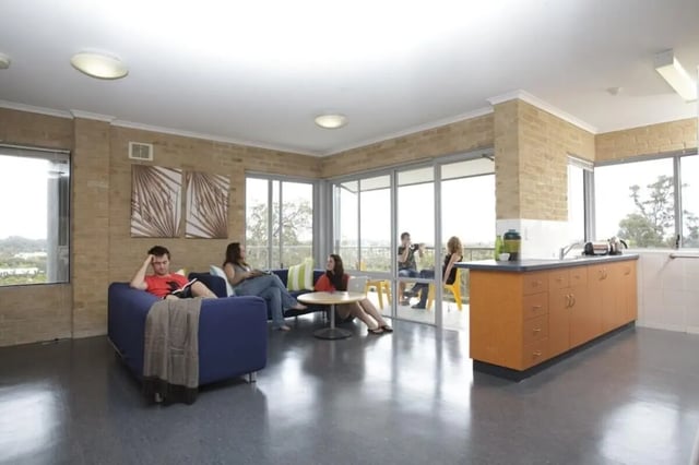 Students relaxing on couch kitchen counter view living room at ECU Village Bunbury in Bunbury Student Accommodation