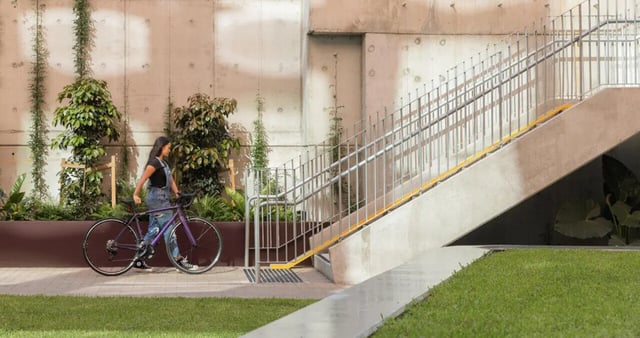 Woman with bicycle walking near stairs exterior at Iglu Mascot in Sydney Student Accommodation