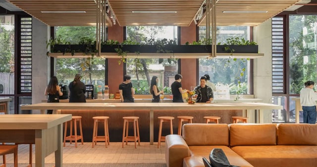 People gather at counter with stools and sofas living room at Iglu Mascot in Sydney Student Accommodation