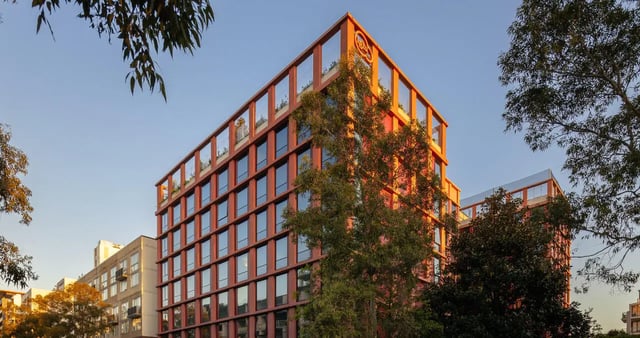 Red apartment building with trees exterior at Iglu Mascot in Sydney Student Accommodation