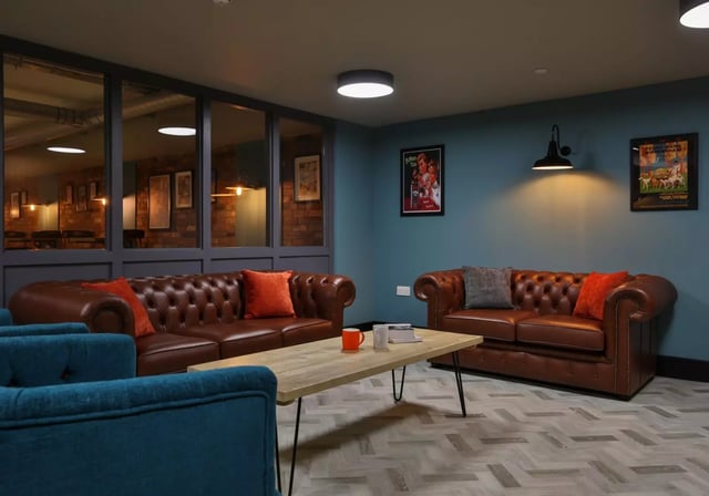 Brown chesterfield sofas with orange pillows living room at iQ Penworks House in Birmingham Student Accommodation