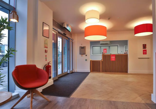 Red armchair fire extinguisher reception desk lobby at iQ Penworks House in Birmingham Student Accommodation