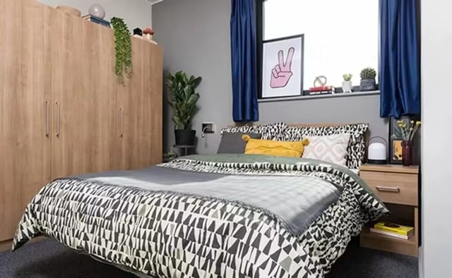 Wardrobe bed with patterned bedding bedside table bedroom at Sky Plaza in Leeds Student Accommodation