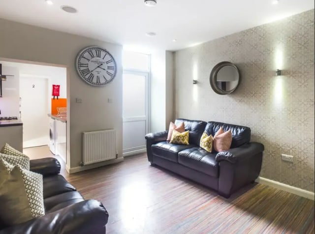 Black leather sofas, patterned wallpaper, large clock living area at 17 Carlton Road in Stoke-On-Trent Student Accommodation