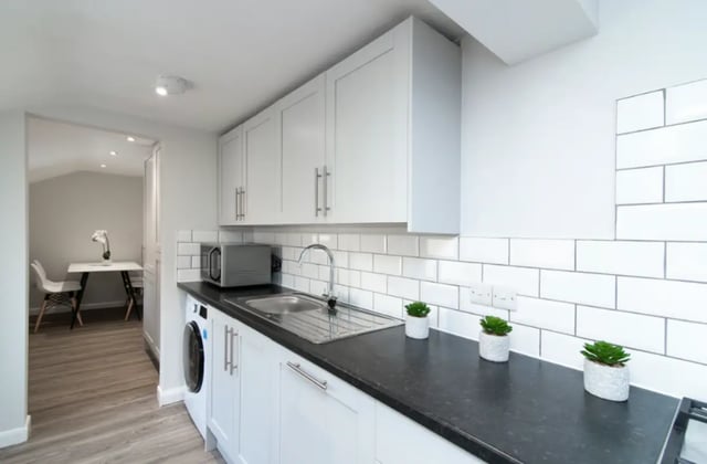 Kitchen with white cabinets dark countertops microwave and plants kitchen at 9 Queen Anne Street in Stoke-On-Trent Student Accommodation