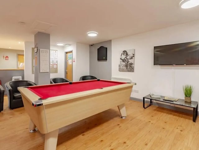 Pool table, chairs, and television in common area at The Print House in Loughborough Student Accommodation