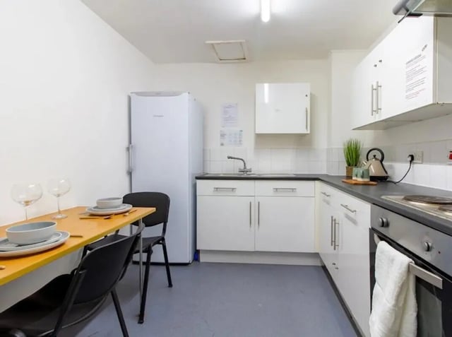 Table chairs refrigerator and sink kitchen at The Print House in Loughborough Student Accommodation