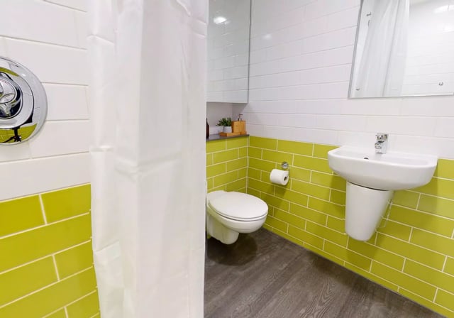 Toilet sink shower curtain and shower controls bathroom at iQ Aldgate in London Student Accommodation