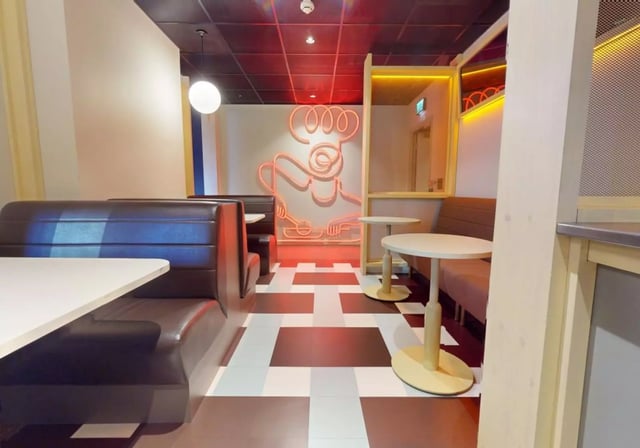 Booths neon chef artwork and tables communal area at iQ Aldgate in London Student Accommodation