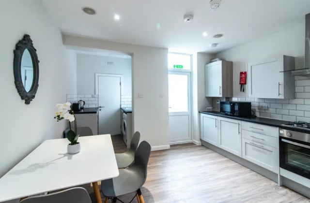 White table chairs mirror oven cabinets kitchen at 18 Cauldon Road in Stoke-On-Trent Student Accommodation
