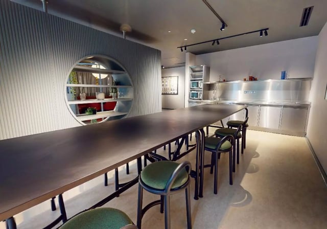 Long table and chairs with kitchen area at iQ City in London Student Accommodation