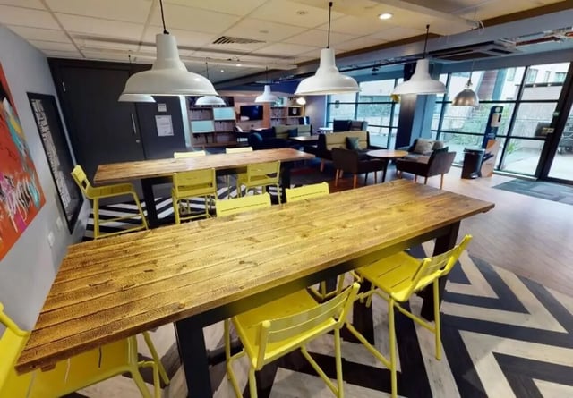 Wooden tables yellow chairs communal area at iQ Marsden House in Leeds Student Accommodation