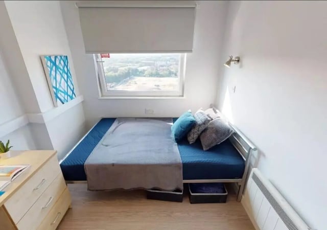 Bed with blue mattress grey blanket pillows bedroom at iQ Marsden House in Leeds Student Accommodation