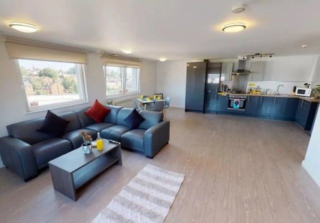 Modern living area with grey sectional sofa kitchen living room at iQ Marsden House in Leeds Student Accommodation