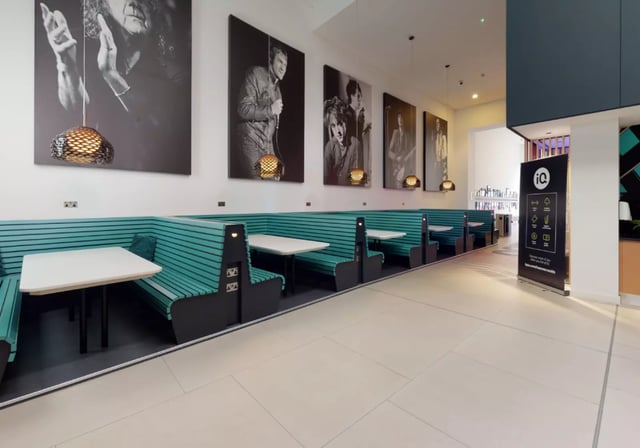 Teal booths with white tables and black chairs common area at iQ Hammersmith in London Student Accommodation