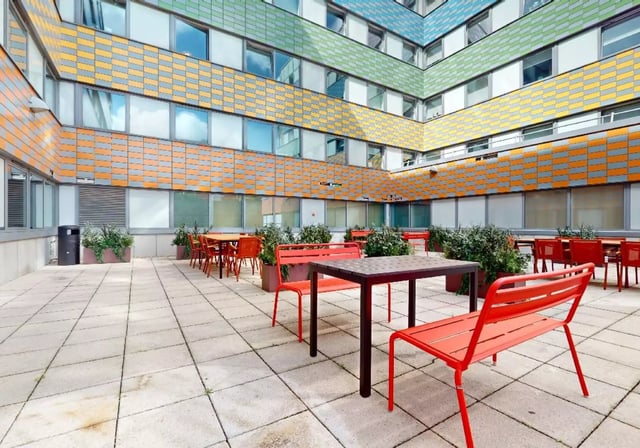 Outdoor patio with tables chairs and plants exterior at iQ Highbury in London Student Accommodation