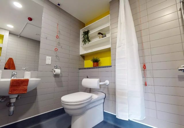 Sink toilet shelves and shower curtain bathroom at iQ Highbury in London Student Accommodation