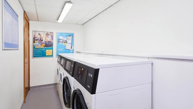 Row of washing machines with posters laundry room at The Moor in Sheffield Student Accommodation