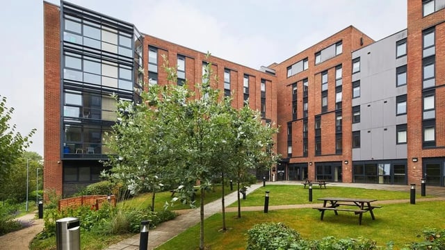Modern brick building with trees and picnic tables exterior at Collegiate Riverside Way Winchester in Winchester Student Accommodation