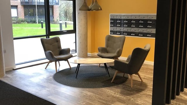 Three grey chairs surrounding oval coffee table seating area at Collegiate Riverside Way Winchester in Winchester Student Accommodation