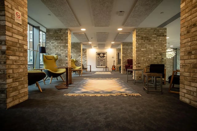 Chairs rugs guitar art in communal living room at Pablo Fanque House in Norwich Student Accommodation