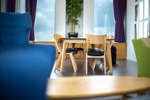 Wooden chairs and table with blue sofa living room at Pablo Fanque House in Norwich Student Accommodation