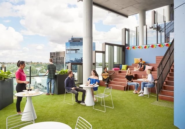 People relaxing on a rooftop lounge area. at Scape Toowong in Brisbane Student Accommodation