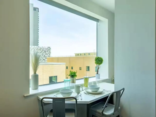 Table chairs place settings plants window dining area at Redvers Tower in Sheffield Student Accommodation