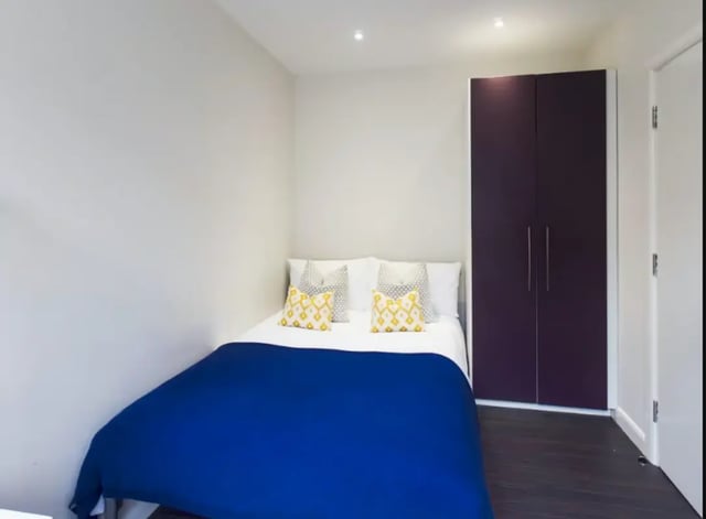 Bed with blue cover and patterned pillows bedroom at 23 Carlton Road in Stoke-On-Trent Student Accommodation