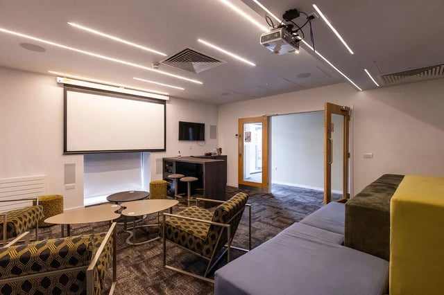 Projector screen couches chairs tables and stools common room at Merlin Point in Coventry Student Accommodation