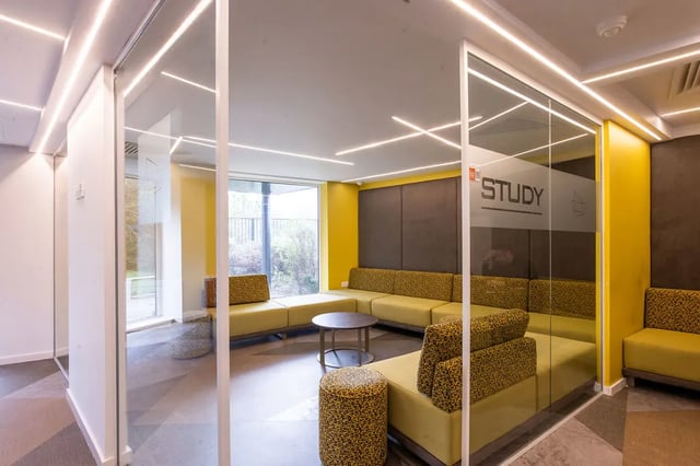 Glass study room with yellow sectional sofa living room at Merlin Point in Coventry Student Accommodation