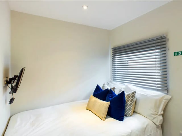 Bed with pillows TV on wall bedroom at 21 Queen Anne Street in Stoke-On-Trent Student Accommodation