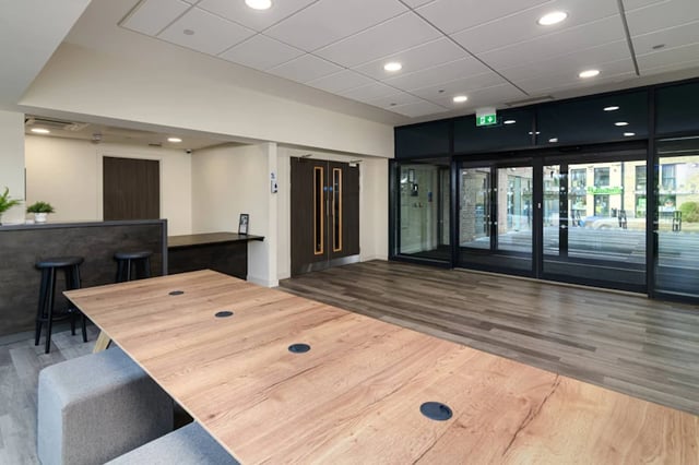 Wooden table with stools near reception lounge area at Stanley Studios in Southampton Student Accommodation