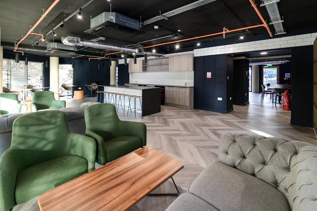 Green chairs kitchen island and wooden table communal area at Stanley Studios in Southampton Student Accommodation