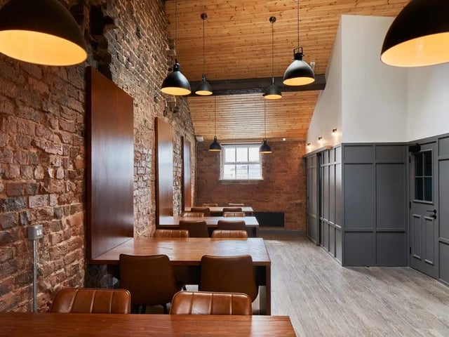 Wooden tables brown chairs exposed brick common area at The Lantern in Liverpool Student Accommodation
