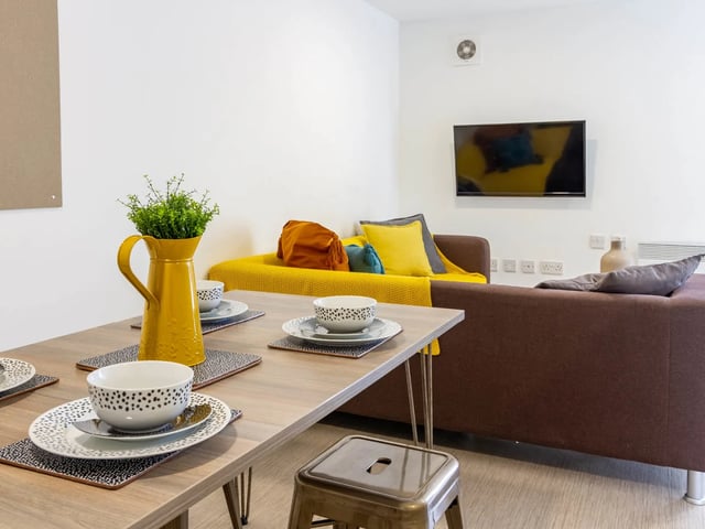 Dining table with yellow vase and sofa living room at The Lantern in Liverpool Student Accommodation