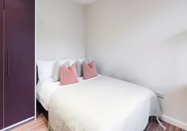 Purple wardrobe white bed with patterned pillows bedroom at 85 Seaford Street in Stoke-On-Trent Student Accommodation