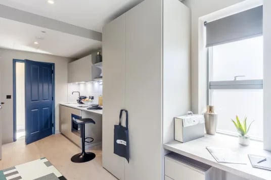 Modern kitchen counter with bar stool and blue door kitchen at The Garage Egham in Egham Student Accommodation
