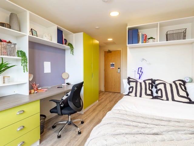 Desk chair bed shelving and yellow wardrobe bedroom at The Barn in Exeter Student Accommodation