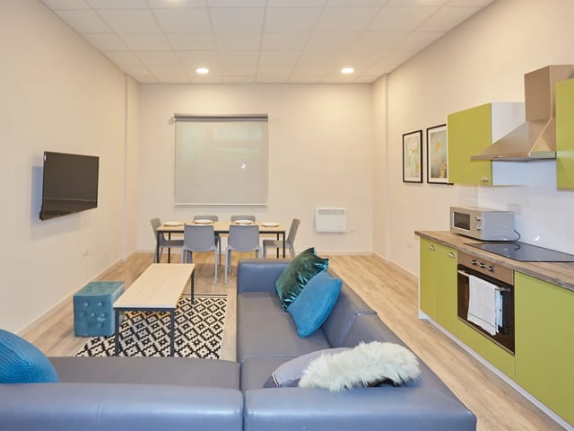 Modern living area with sofas dining table and kitchen living area at The Barn in Exeter Student Accommodation