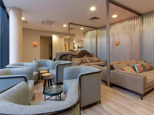Sofas armchairs stools with patterned pillows common area at The Barn in Exeter Student Accommodation