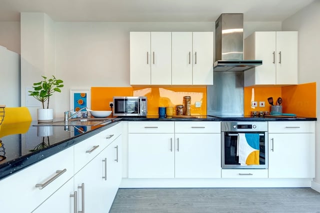 Modern white kitchen with orange backsplash kitchen at Central Living in Exeter Student Accommodation
