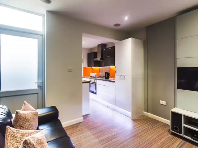 Leather sofa kitchen visible with orange backsplash living room at 42 Watford Street in Stoke-On-Trent Student Accommodation