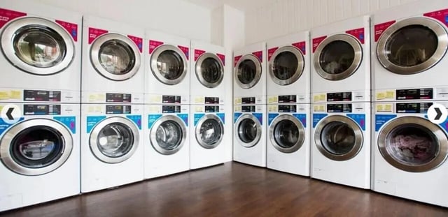 Stacked washing machines with control panels laundry room at Denmark Road in Manchester Student Accommodation