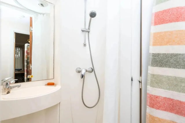 Sink showerhead mirror and striped curtain bathroom at Grafton Street in Manchester Student Accommodation
