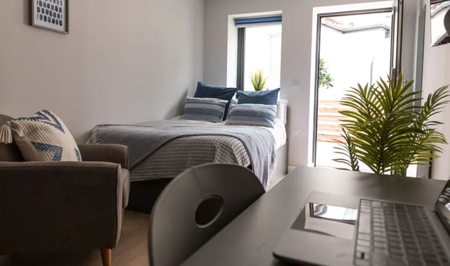 Bed armchair laptop plant window exterior bedroom at Boutique Student Living - Exeter in Exeter Student Accommodation