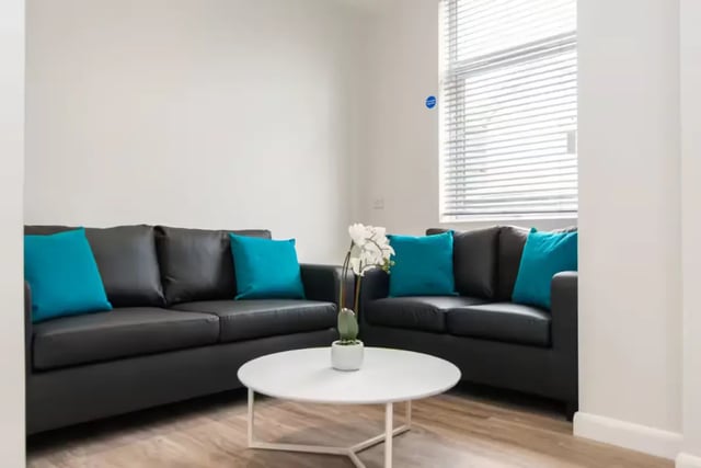 Black sofas teal pillows white table plant living room at 38 Cauldon Road in Stoke-On-Trent Student Accommodation