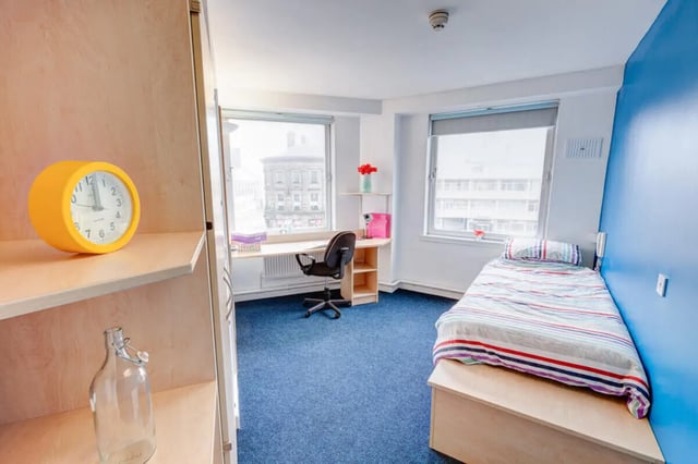 Yellow clock desk chair bed blue wall bedroom at Dunn House in Sunderland Student Accommodation